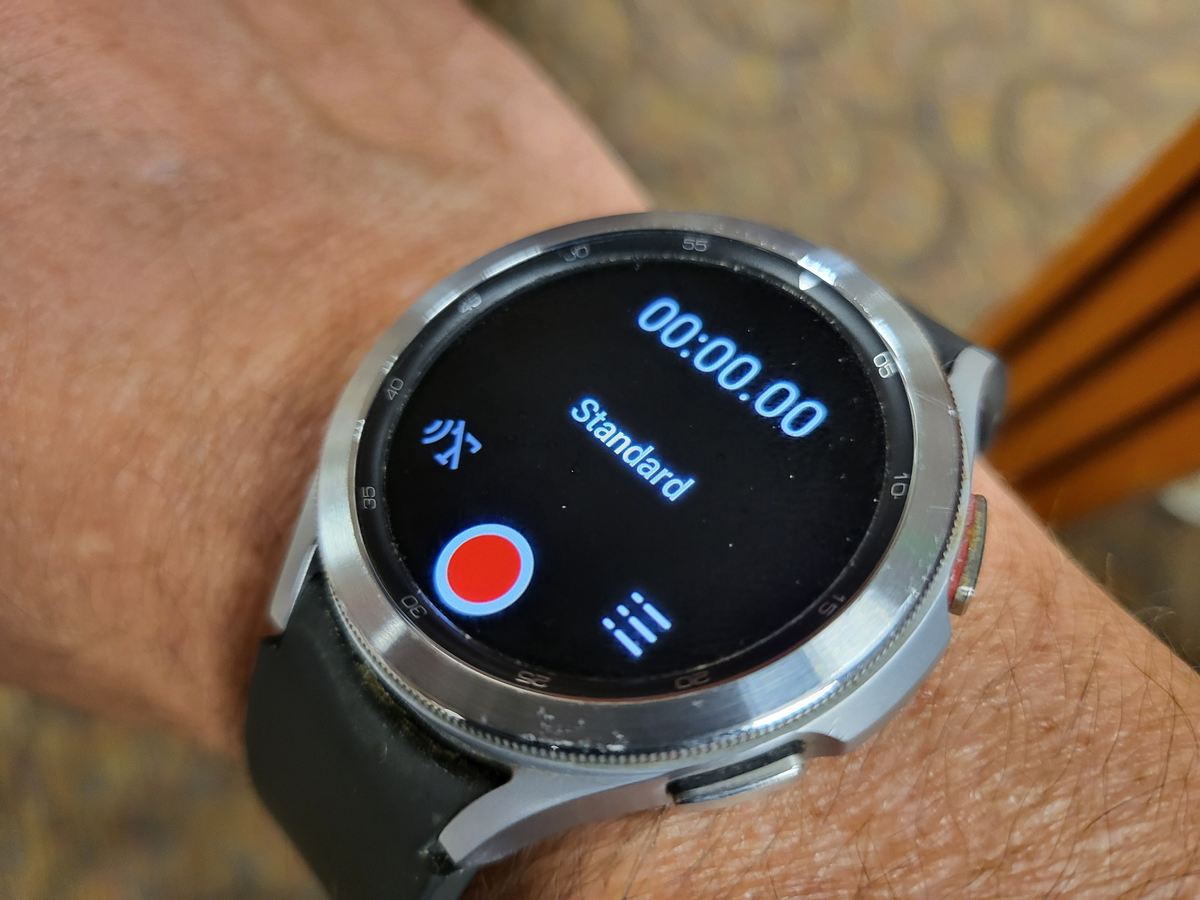 Digital stopwatch app open on a smartwatch, showing a memo screen with a start time of zero seconds, worn on a wrist.